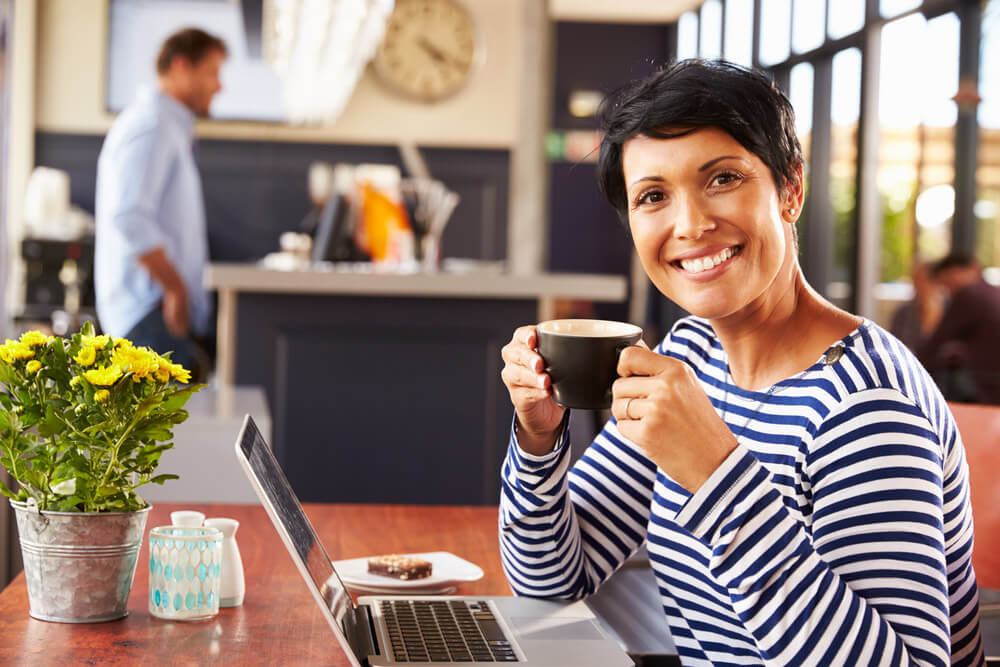 Woman smiling while having a cup of coffee in a coffee house