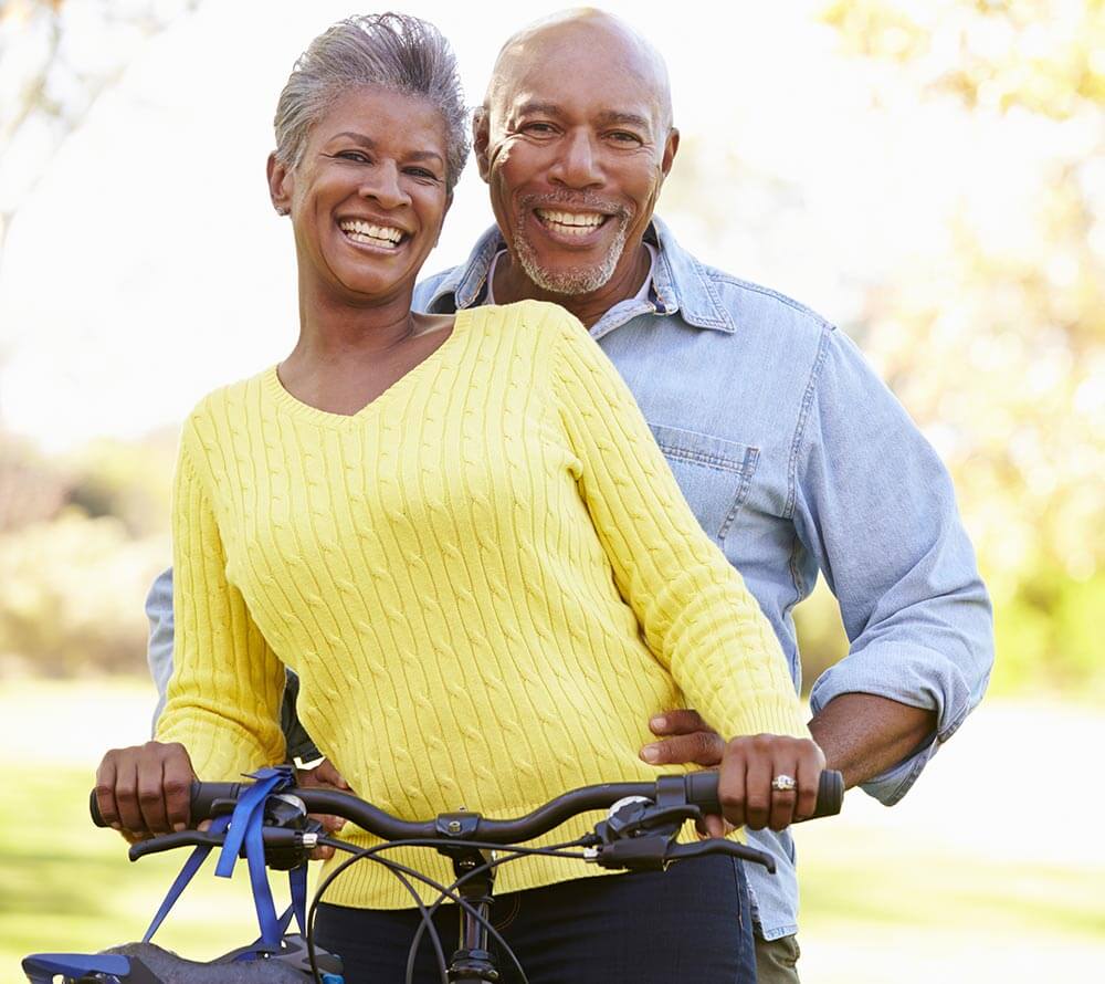 Older couple smiling while riding a bike