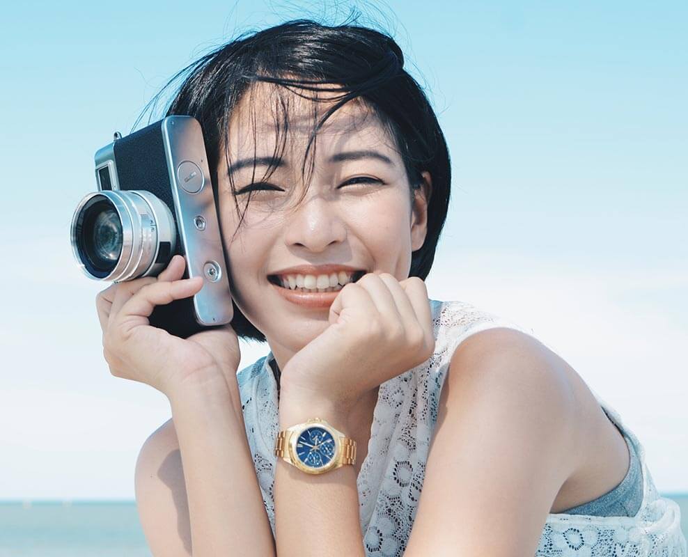 Young adult woman smiling and holding a camera