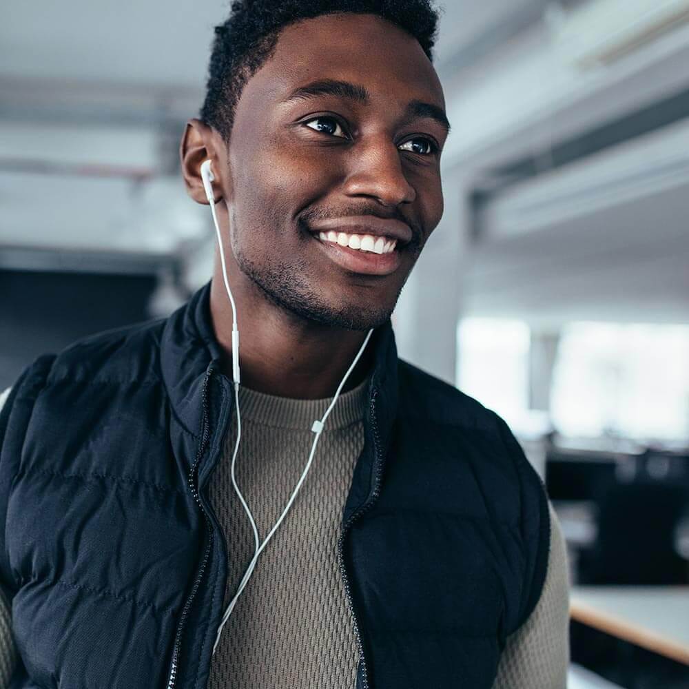 Young adult man smiling and wearing ear buds