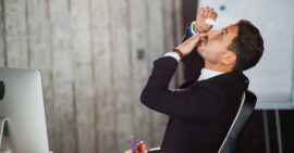 Man at desk adding eye drops to his dry eyes