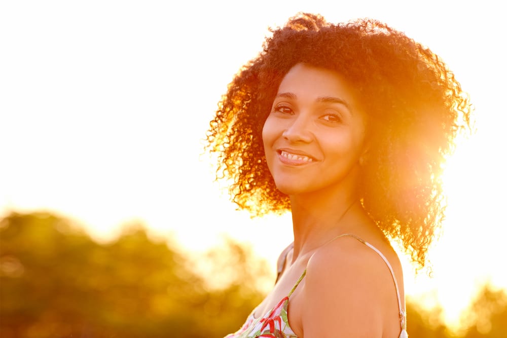 Smiling woman with warm, bright sun in the background