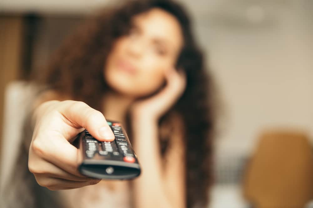 woman holding television remote control