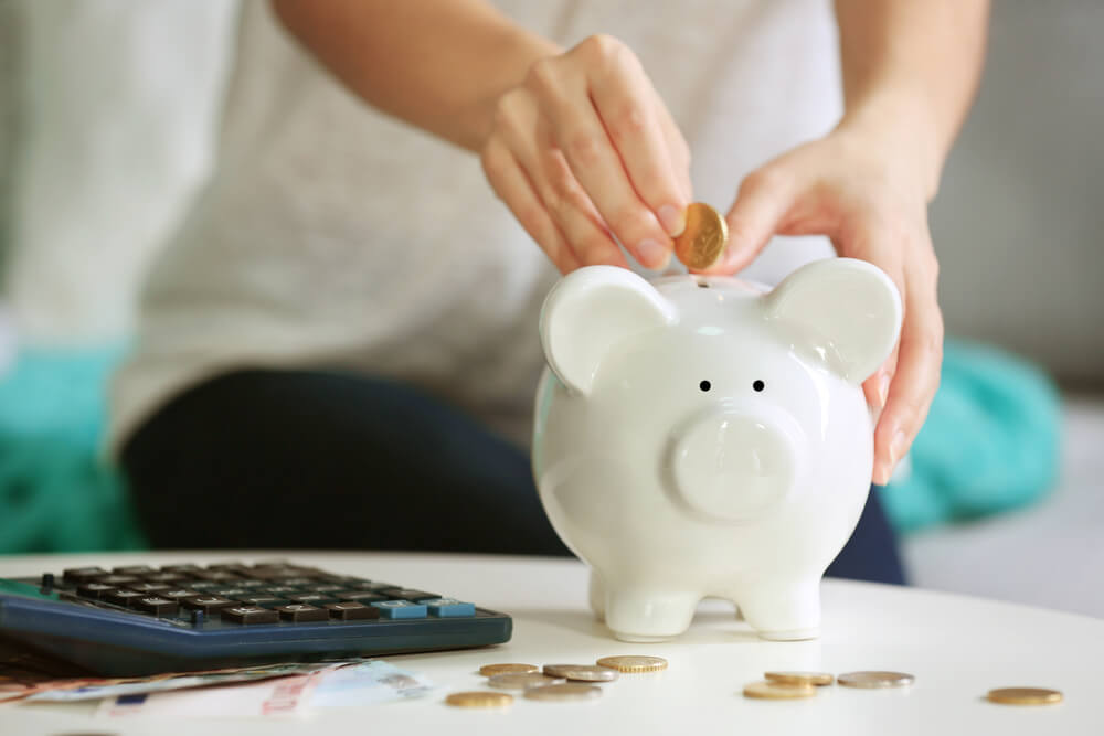 Woman putting a coin into a piggy bank