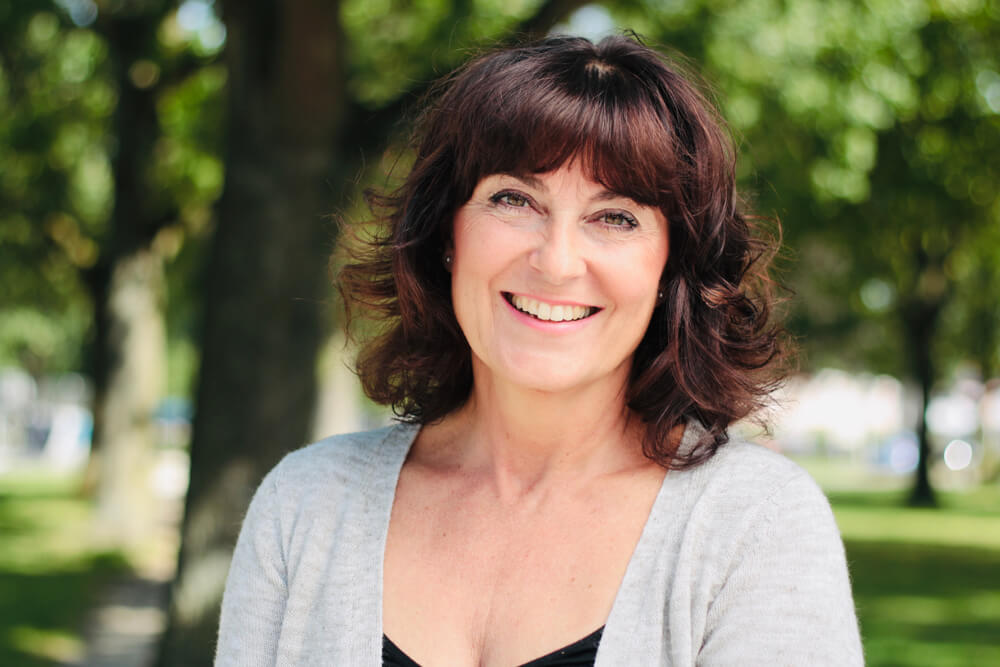 Smiling middle-aged woman with trees in the background